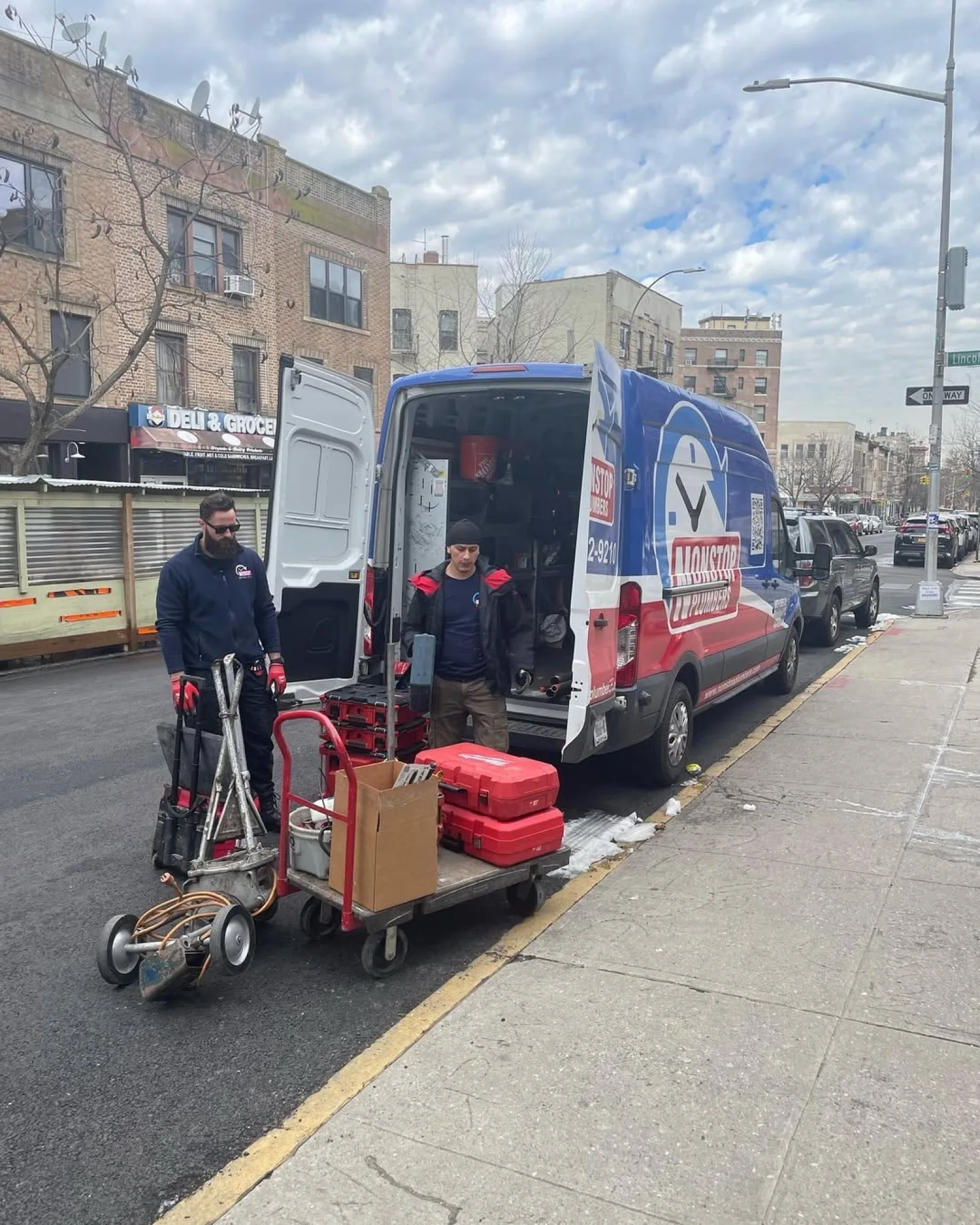 Nonstop Plumbers NY crew unloading tools from a service van on a New York street.