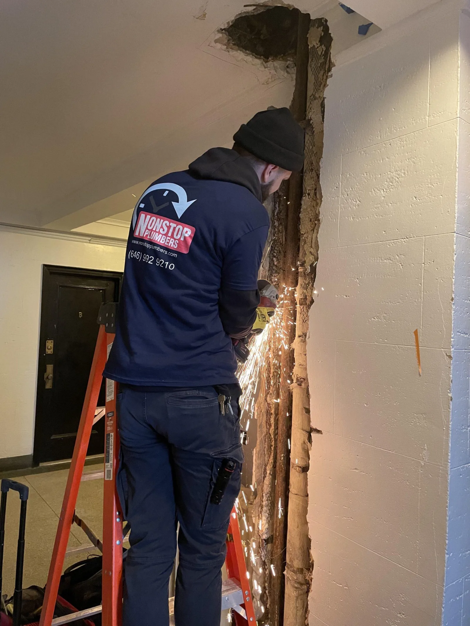 Nonstop Plumbers NY technician repairing exposed piping in a building corridor.