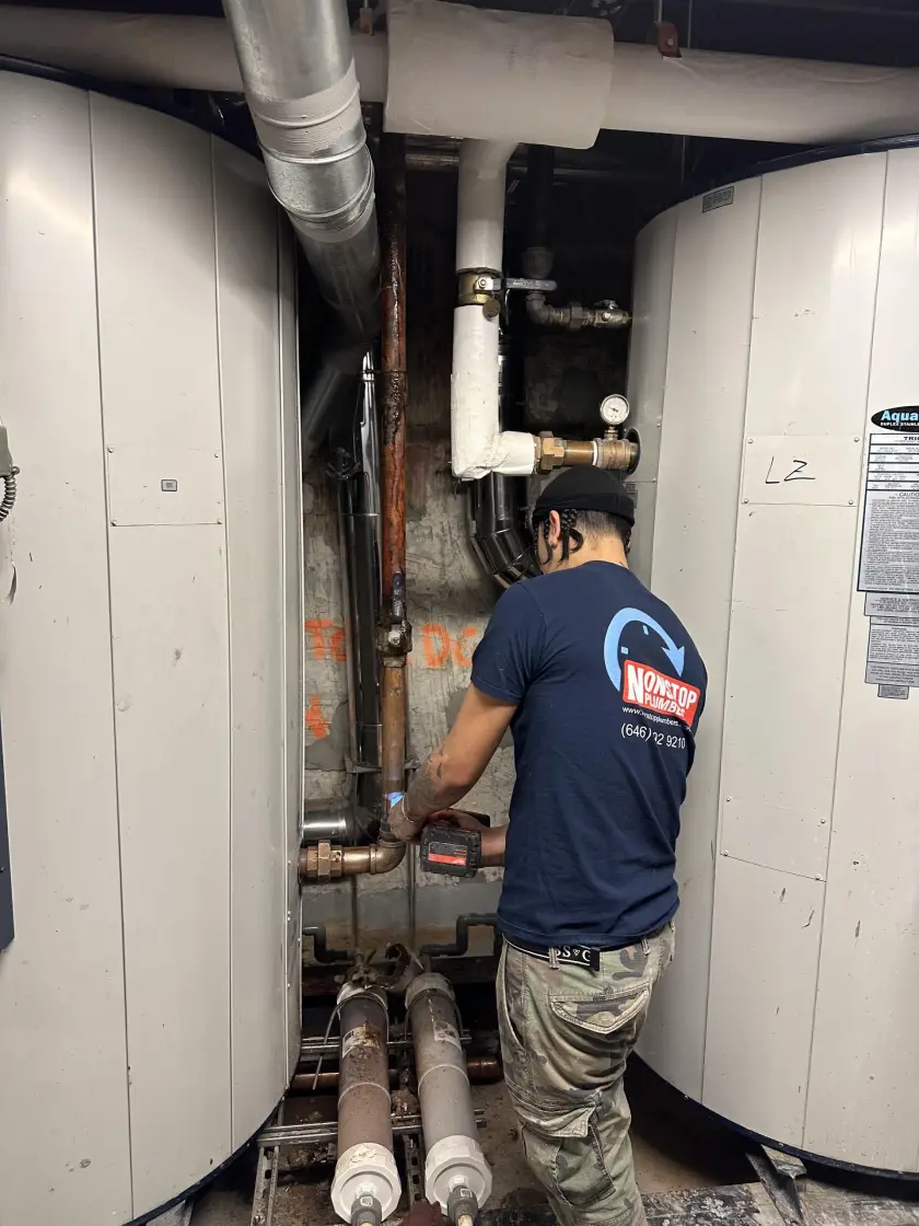 Nonstop Plumbers NY technician repairing plumbing inside a boiler room.